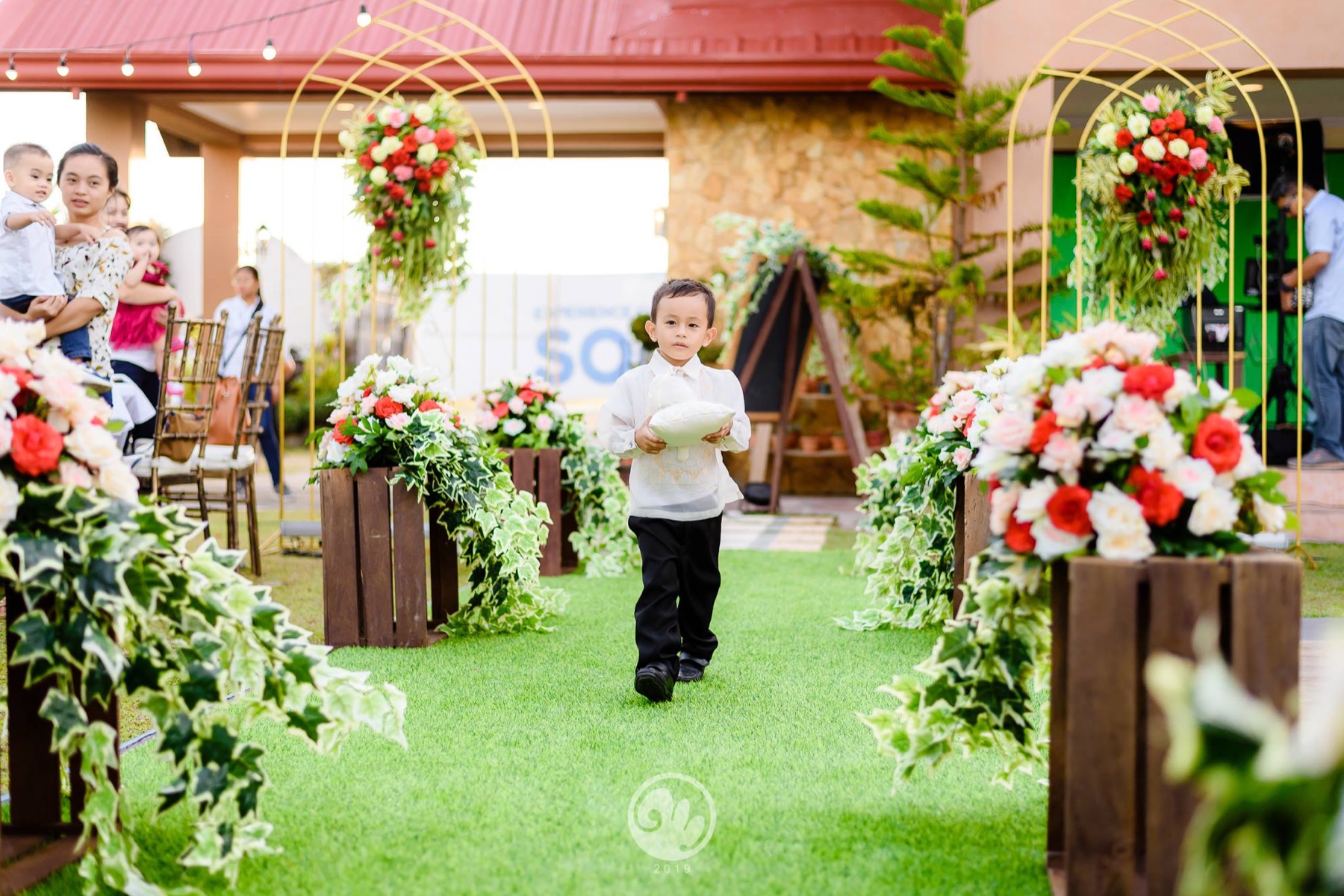 Young ring bearer walking down the garden aisle