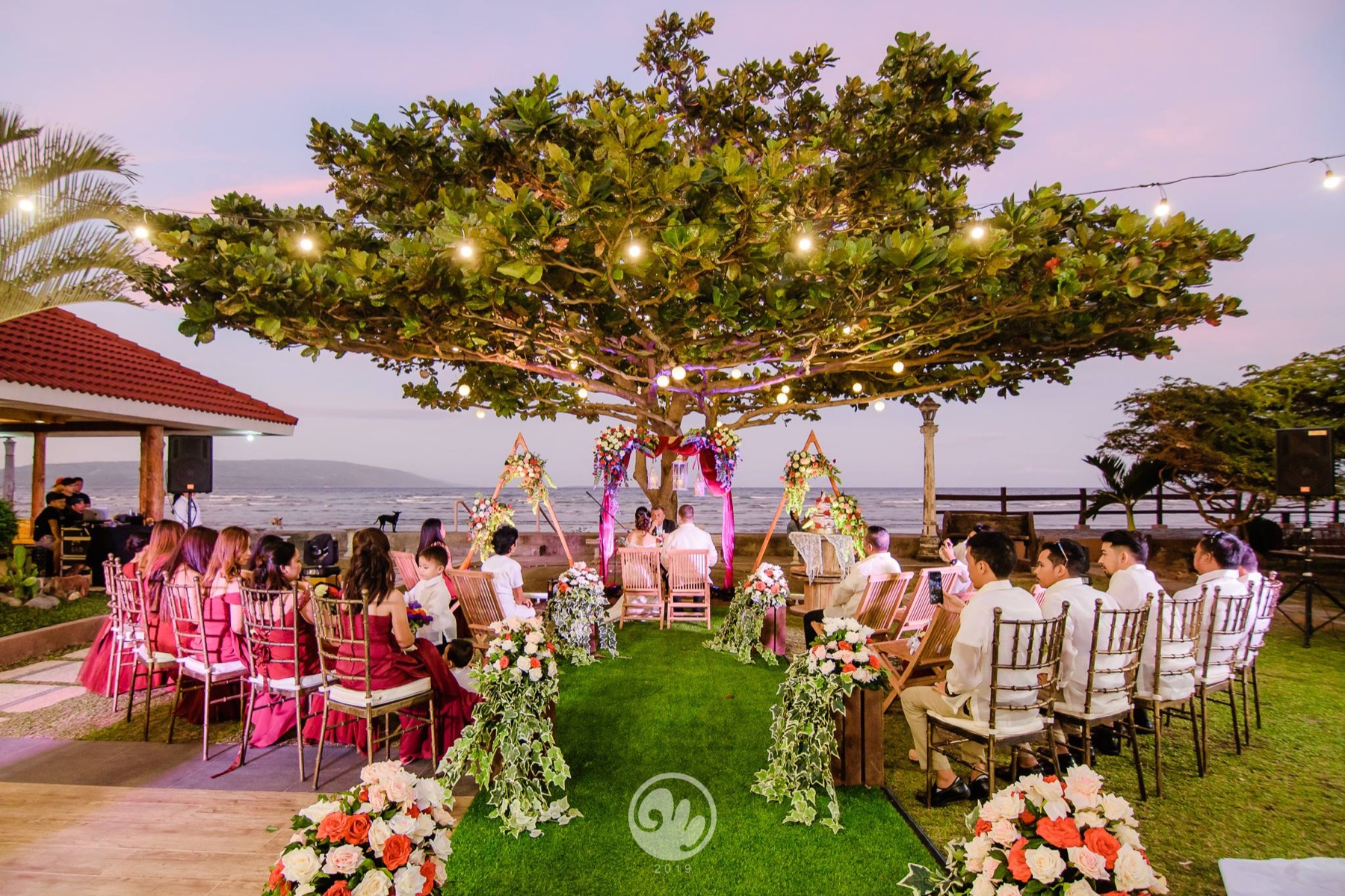 Wide view of a beachfront ceremony under the Talisay tree