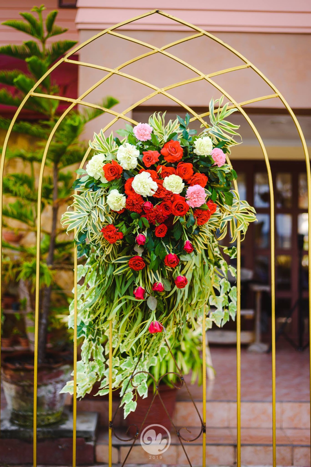 Red and white rose arrangement with tropical greenery