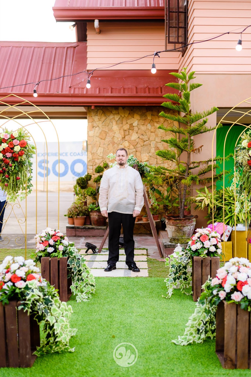 Groom waiting at a flower-lined ceremony aisle