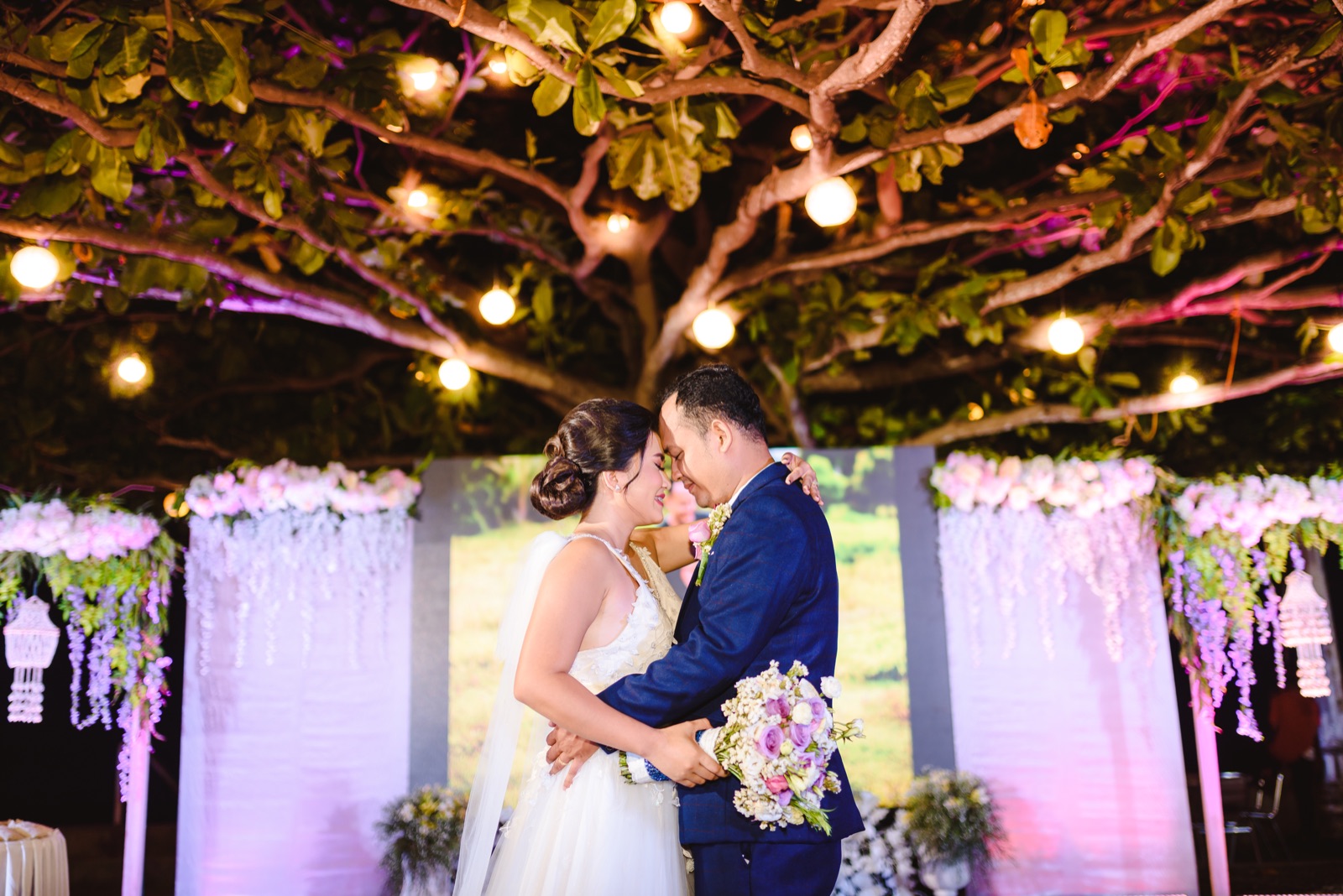 Newlyweds beneath the illuminated Talisay tree